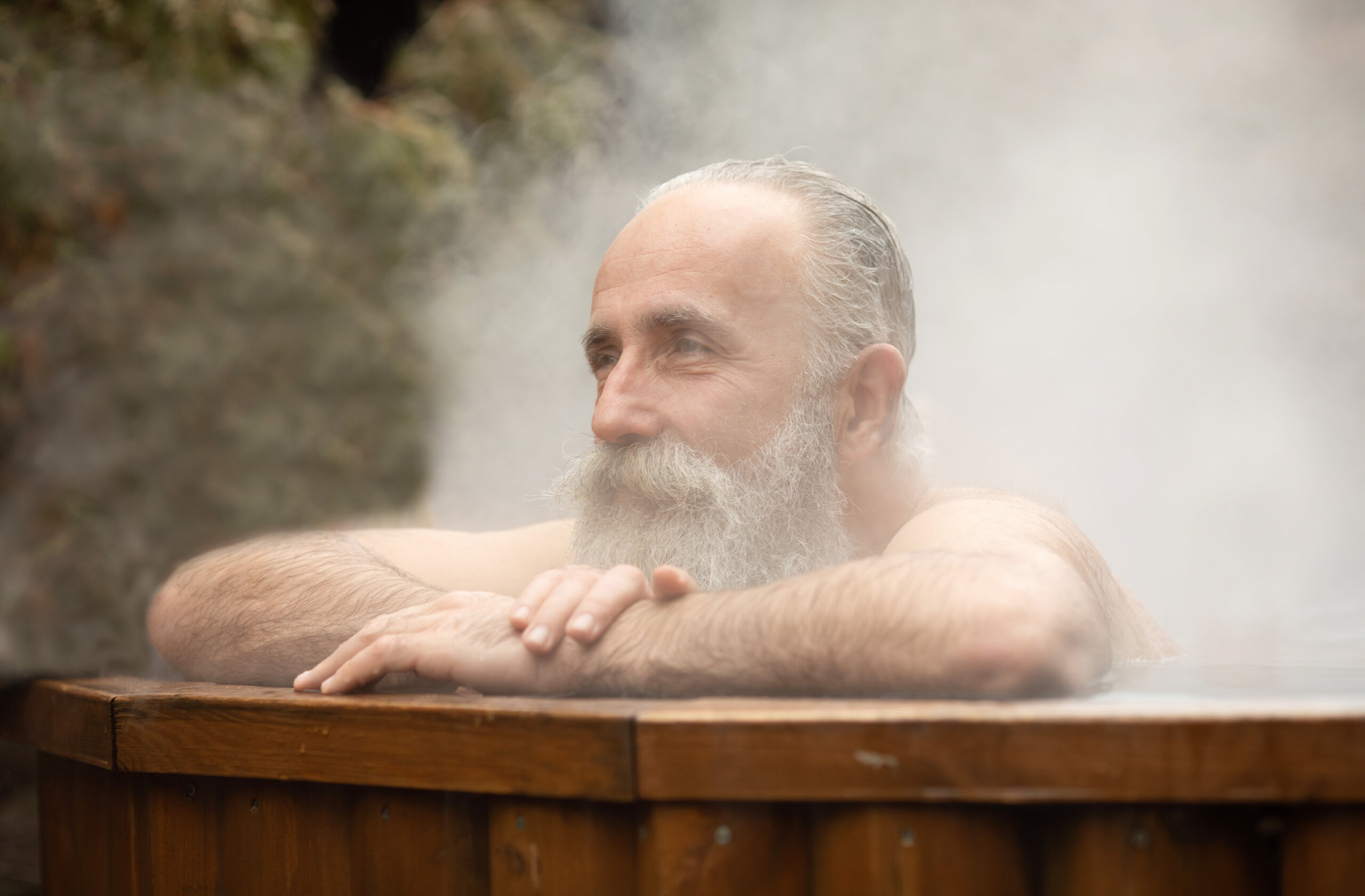 Bearded senior man enjoying thermal bath in thalassotherapy center.